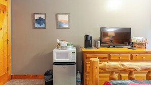 Una habitación funcional con microondas, refrigerador, cómoda de madera y televisor.