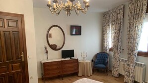 A bedroom with a bed, dresser, mirror, television, chair, and curtains. - Casa Rural Rincón de Ayllón (ayllon)