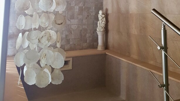 A modern interior with a wooden ceiling, a stone wall, and a decorative white column. - Casa Rural Rincón de Ayllón (ayllon)