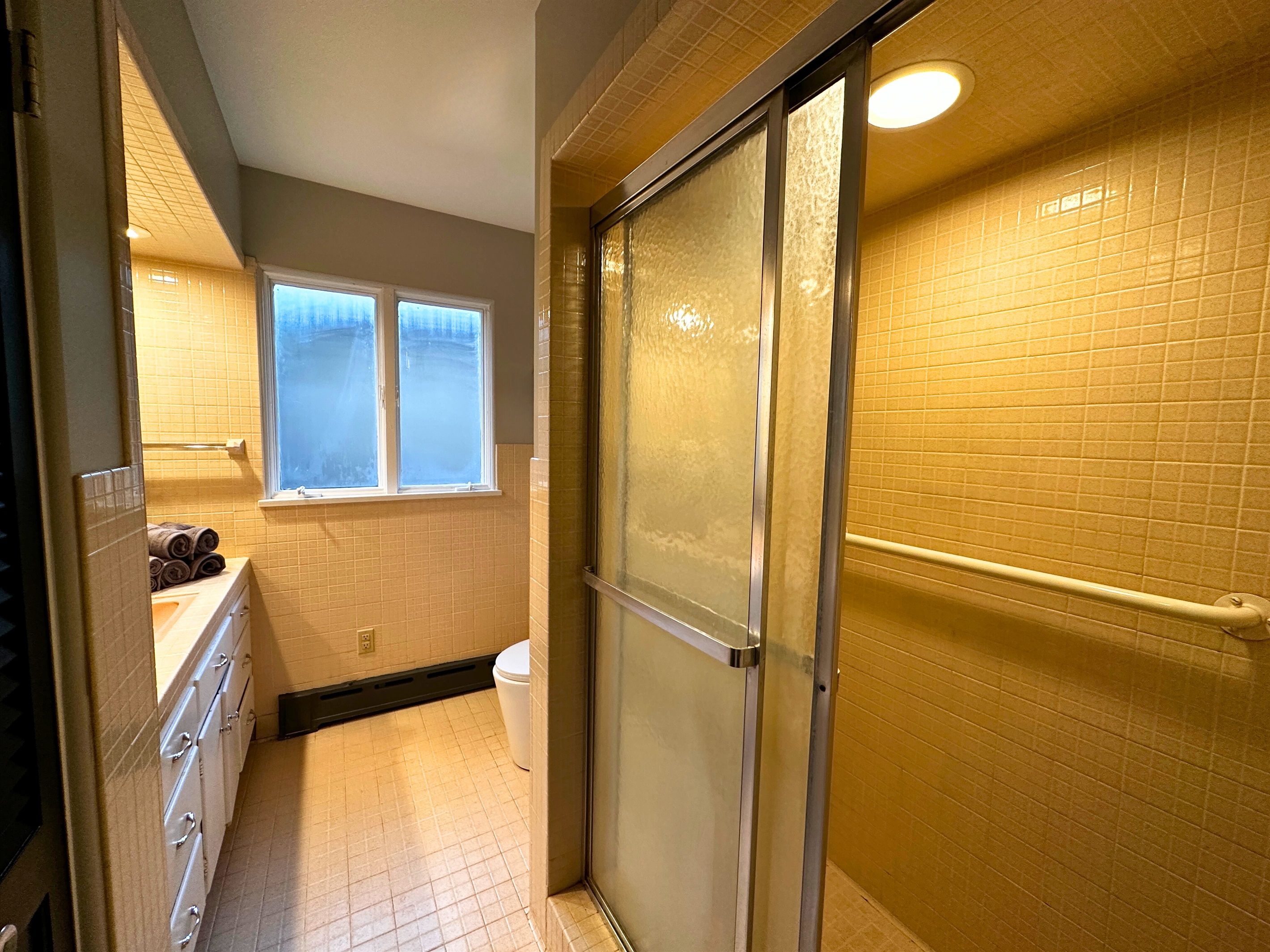 Un baño con ducha, inodoro, lavabo y ventana.