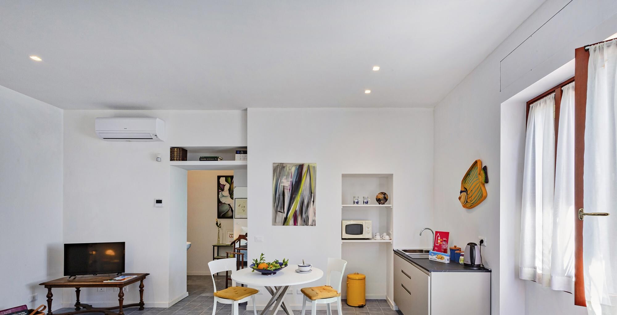 A compact living space with a dining area, kitchenette, and a TV.
