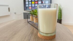 Une bougie posée sur un dessous de verre dans une pièce où un téléviseur affiche des icônes d’applications.