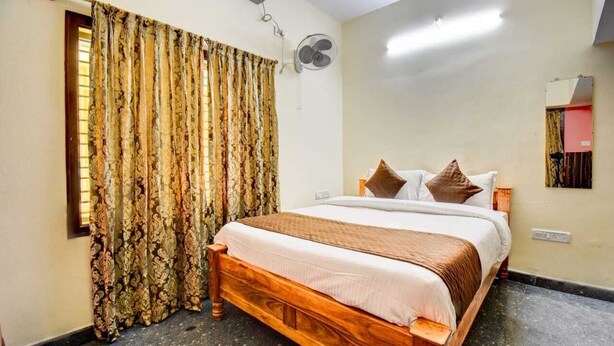 Un dormitorio con cama de madera, ventilador de techo y ventana con cortinas.