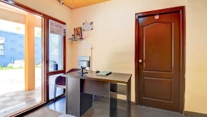 Zona de recepción con escritorio, computadora, silla, puerta y ventana.