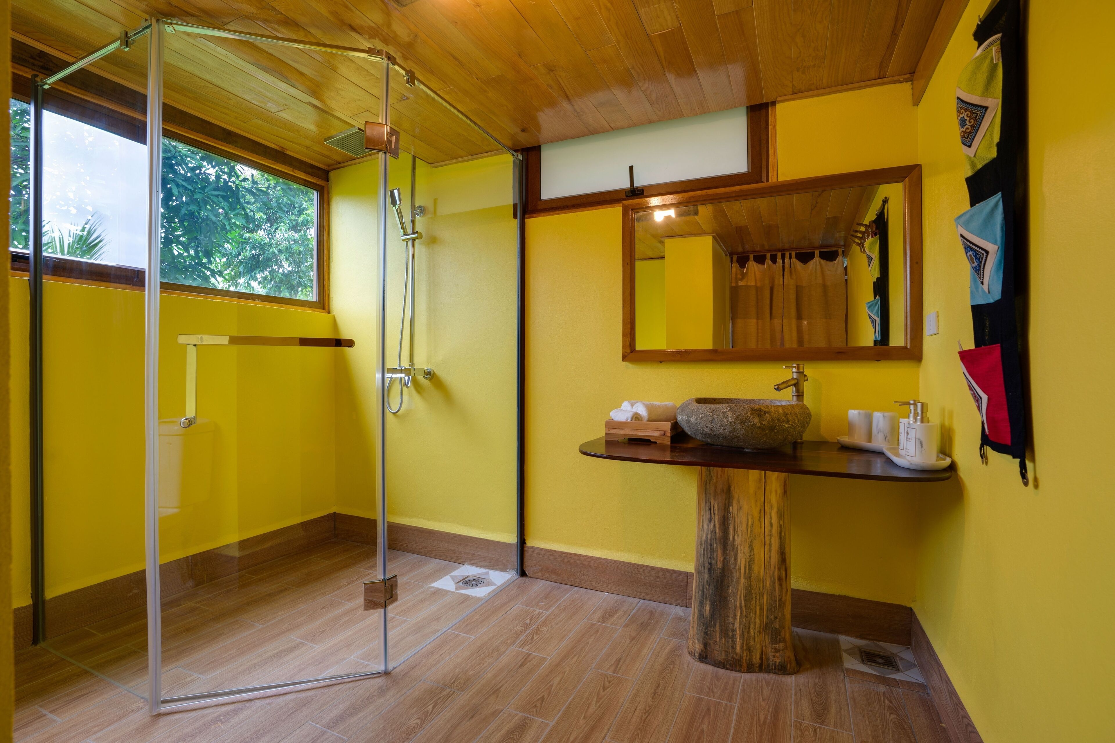 Un baño con cabina de ducha de vidrio, lavabo de madera y un espejo grande.