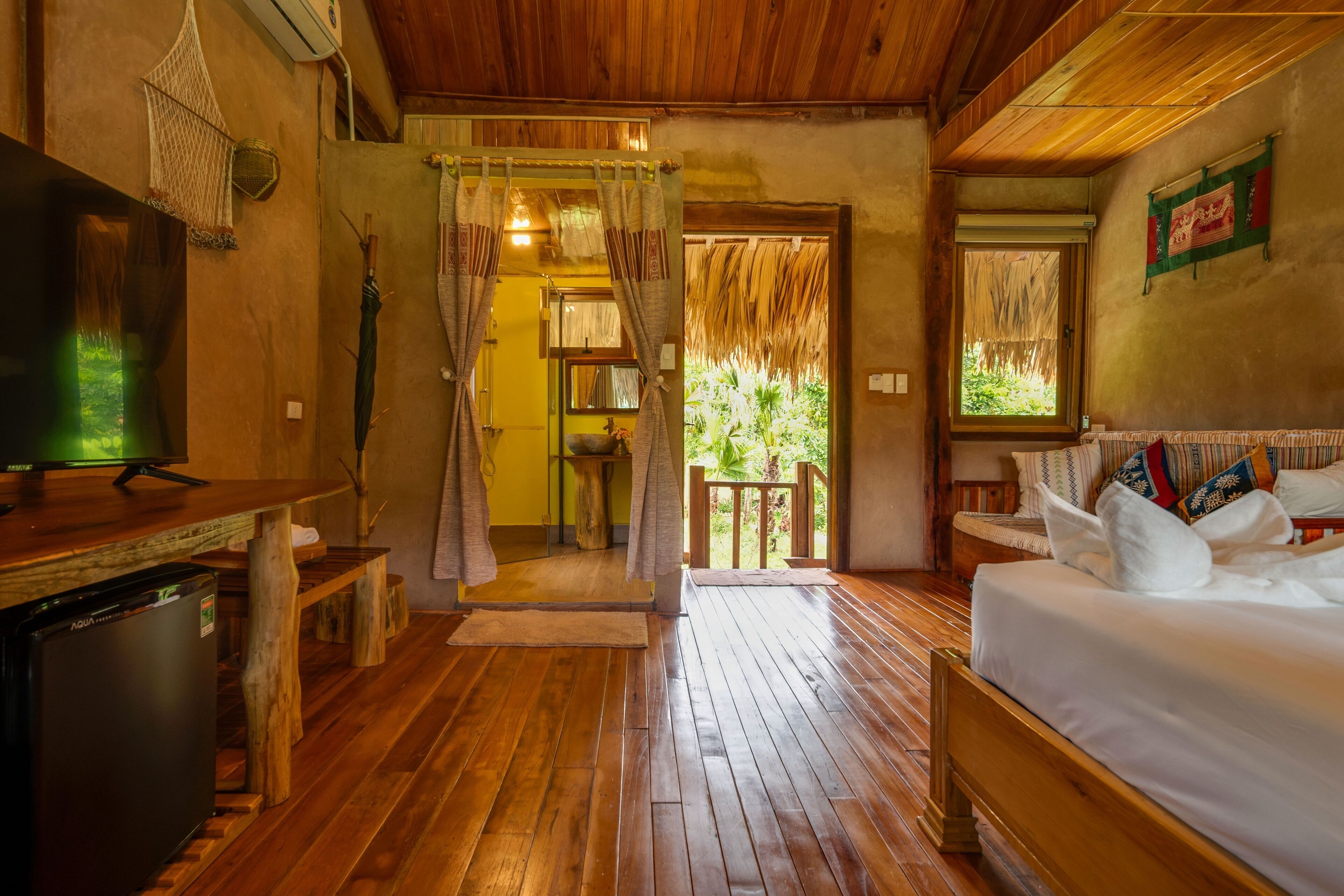 A wooden-floored room with a bed, a TV, and a small table.