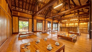 Un intérieur traditionnel en bois, avec des tables dressées pour le repas, de grandes fenêtres et un plafond haut.