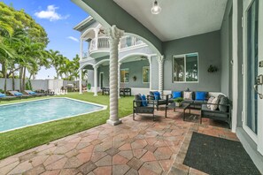 Un espace aménagé au bord de la piscine, comprenant une piscine, des sièges extérieurs et un patio couvert.