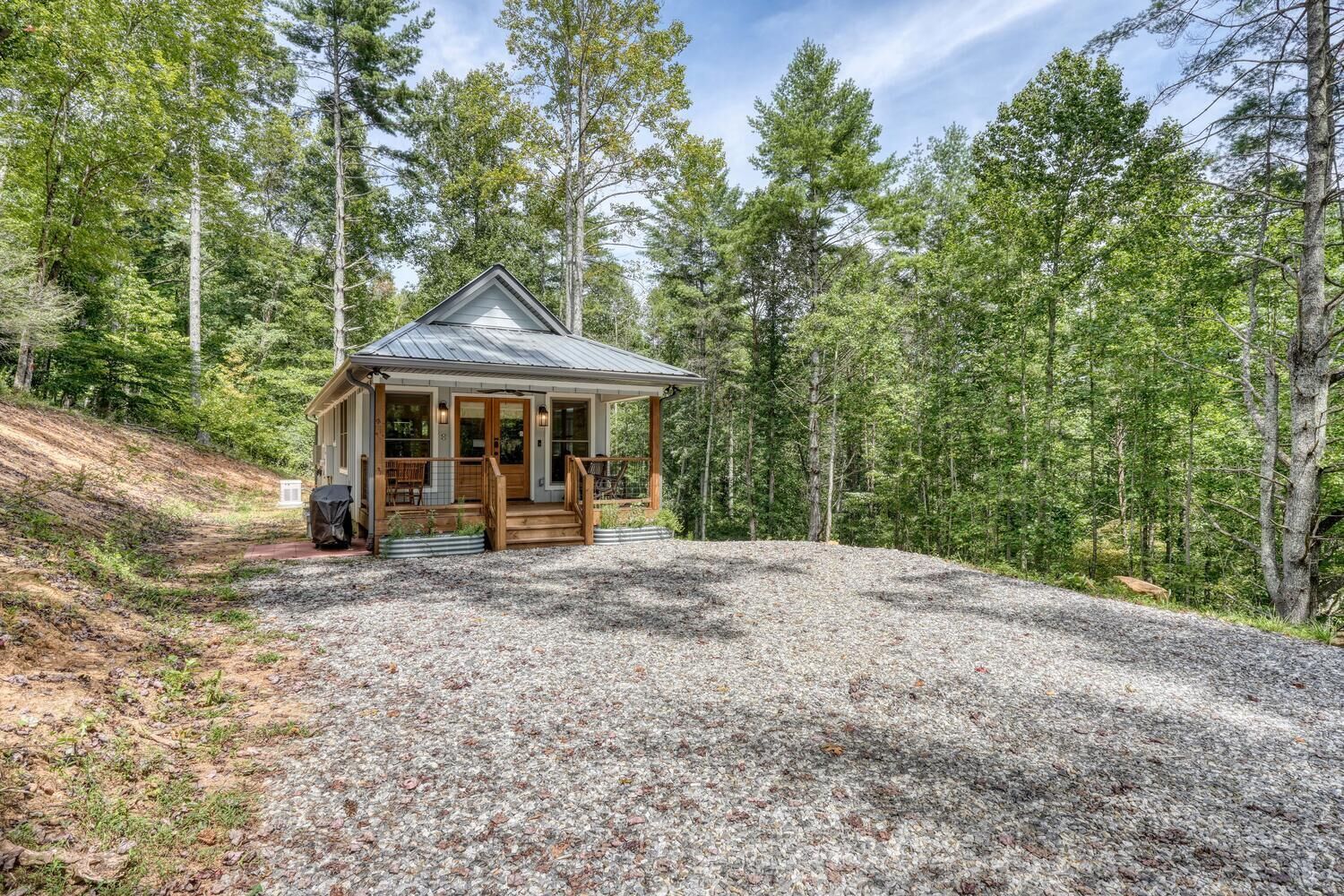 A cabin with a porch, surrounded by a forest.