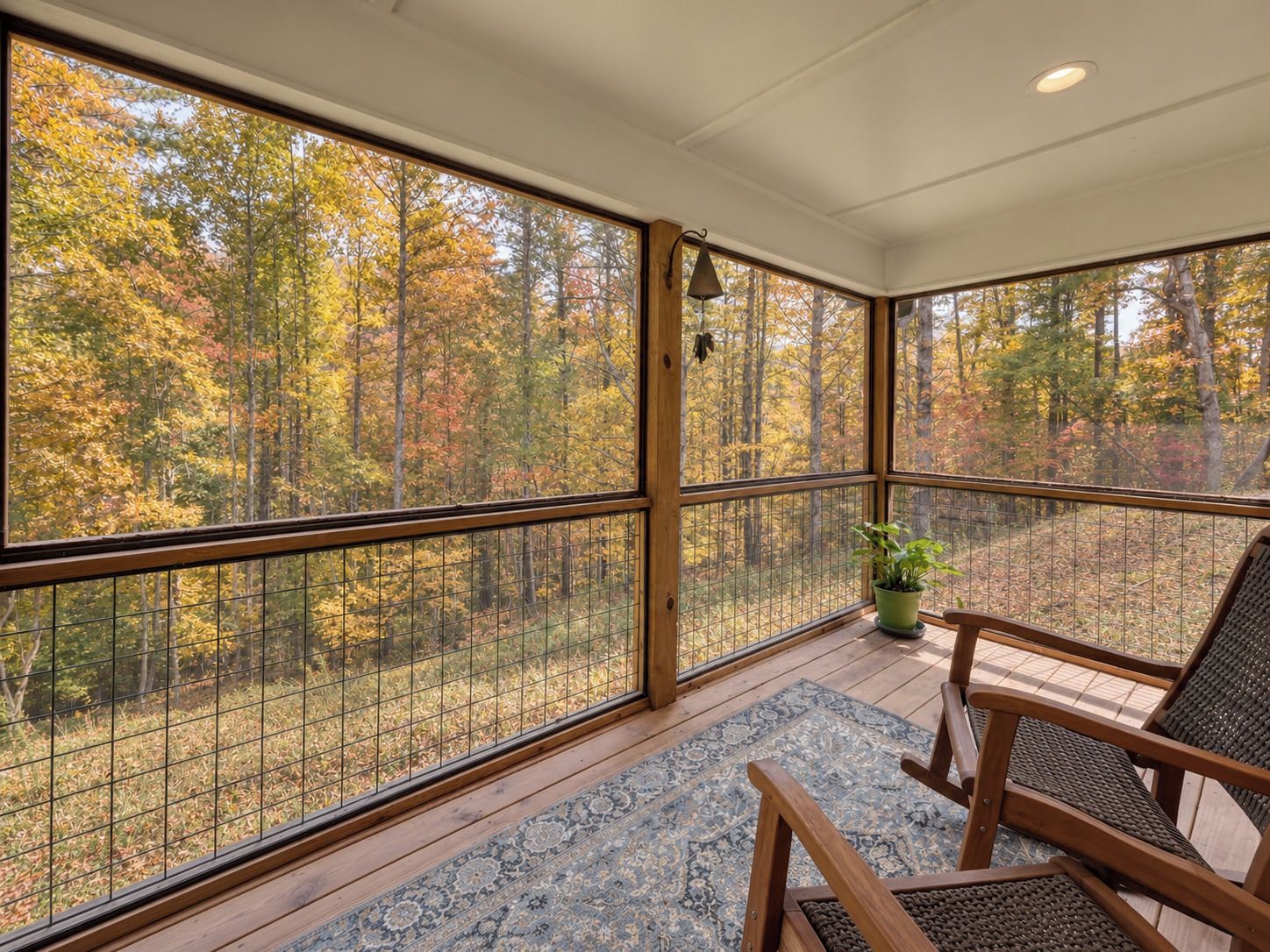 A room with large windows, a wooden floor, and a seating area with a rug.