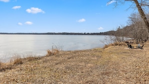 Une vue sur le lac, avec un ciel dégagé, un lac gelé et quelques chaises placées au bord de l’eau.