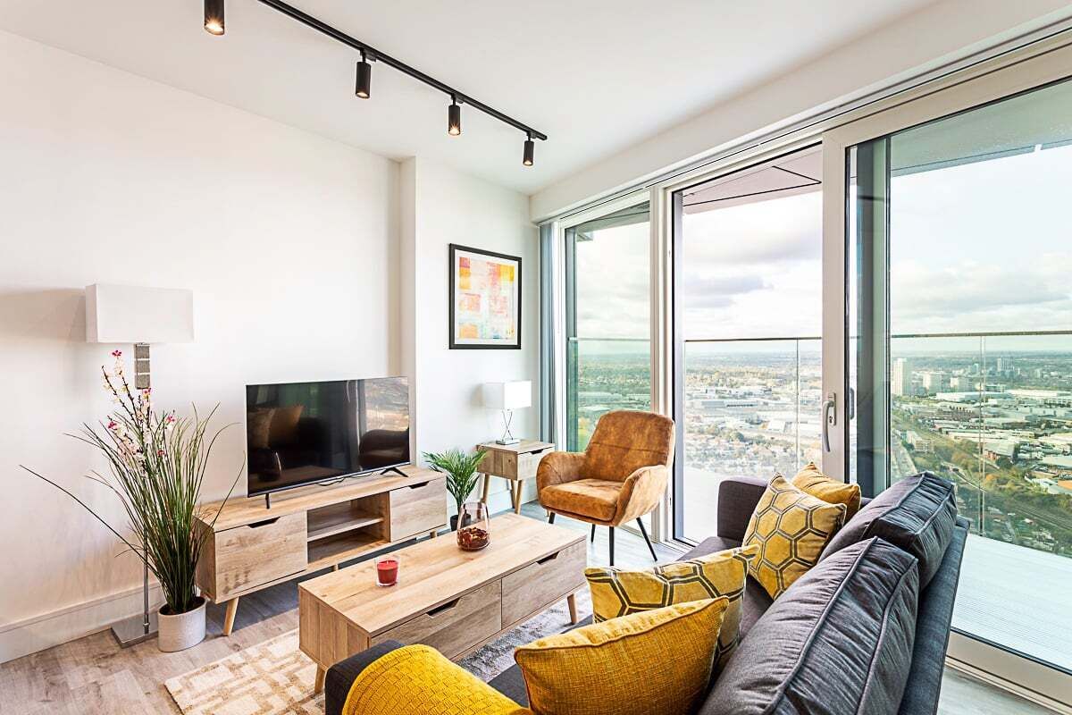 Een moderne woonkamer met een grote televisie, comfortabele zithoek, een salontafel en een groot raam met uitzicht over de stad.