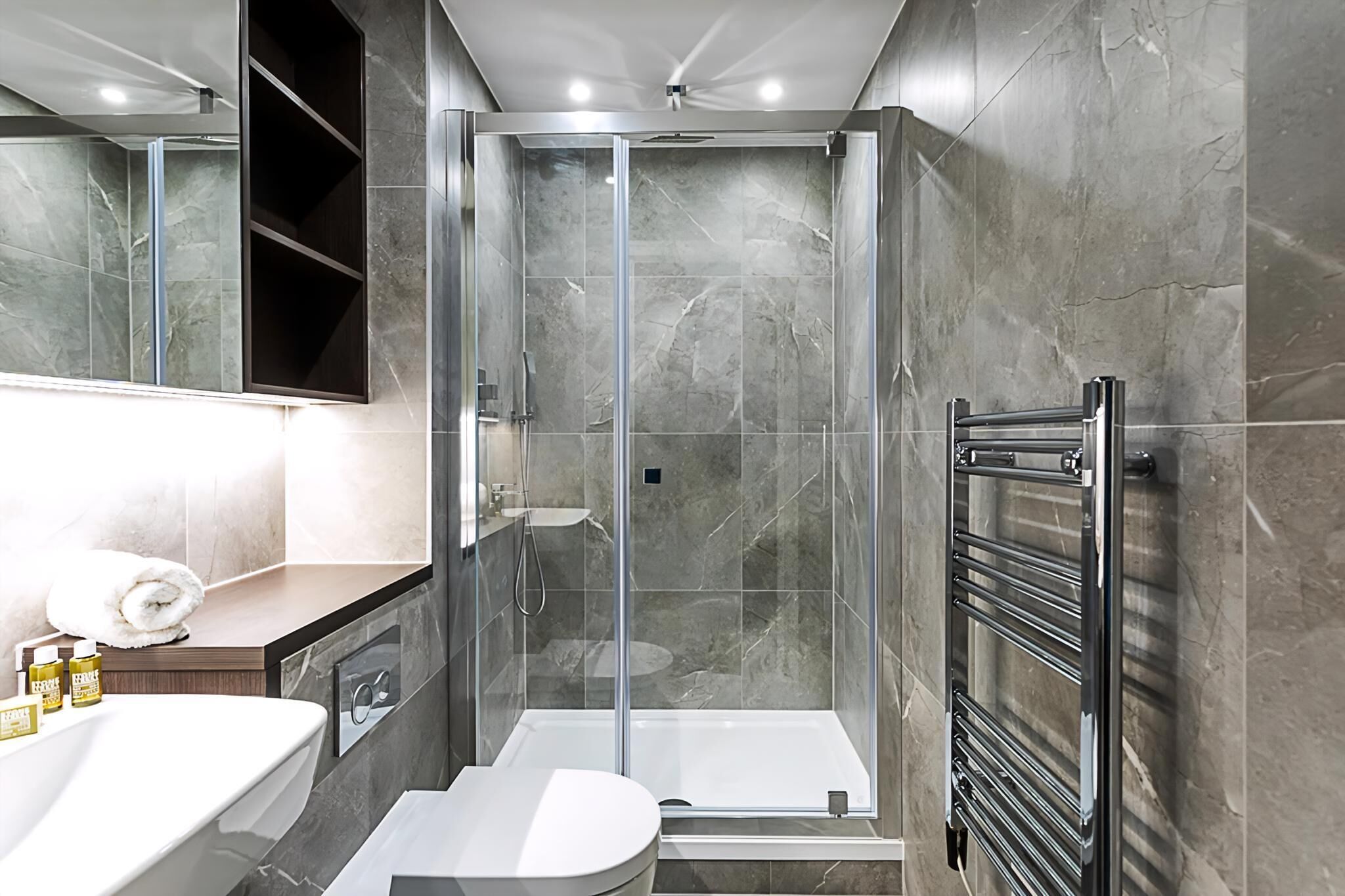 Een moderne badkamer met een douchecabine, een wit wastafelmeubel en een inbouwtoilet.