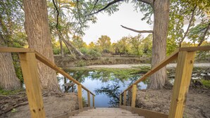 Una escalera de madera que baja a una masa de agua tranquila rodeada de árboles.