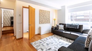 Un salon moderne avec un canapé gris, un tapis à motifs et un élément décoratif mural.