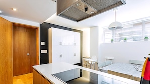 Une cuisine moderne dotée d’une cuisinière intégrée, de meubles en bois et d’une fenêtre donnant sur la ville.