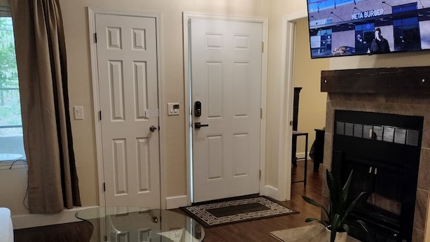 Una sala de estar con una mesa de centro de vidrio, una chimenea y un televisor de pantalla plana montado encima.
