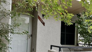 Una casa con fachada blanca, un buzón de madera y un cartel con el número 105.
