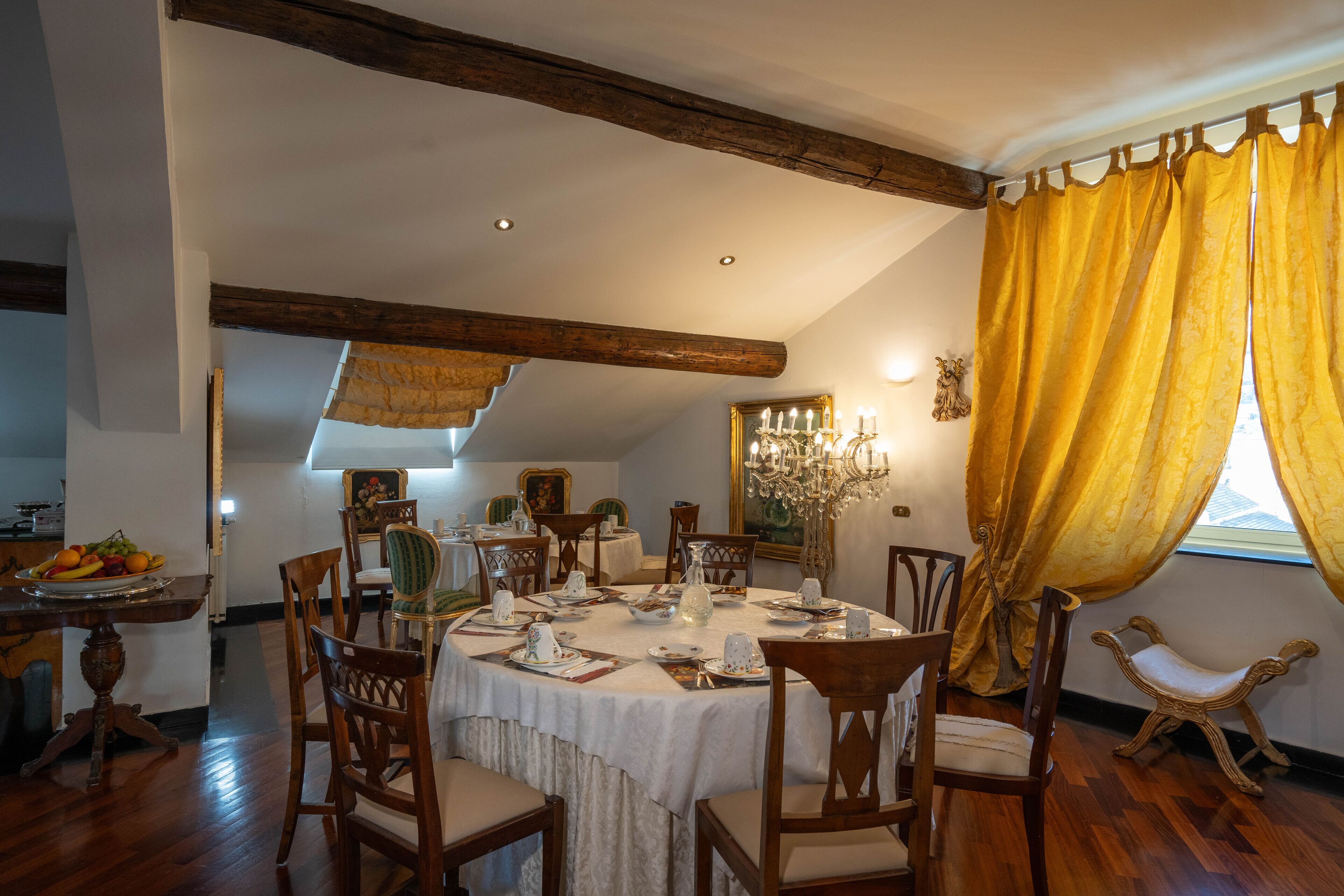 A dining room with a round table set for four, surrounded by wooden chairs.