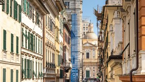 Una calle histórica con edificios de arquitectura clásica y una torre destacada con cúpula.