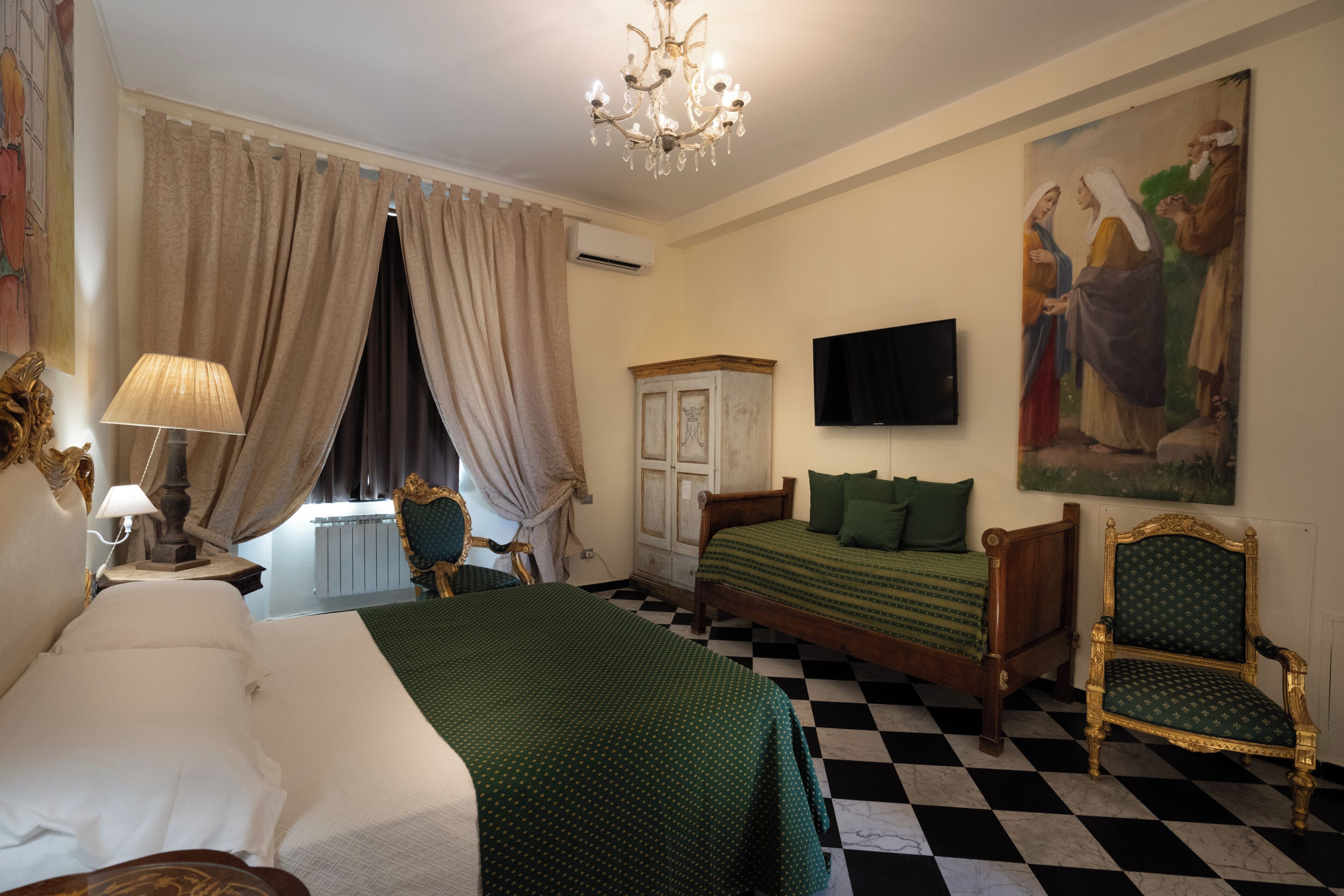 A hotel room with a checkered floor, two beds, a television, a chandelier, and a painting on the wall.