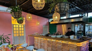 A restaurant with a checkered floor, a bar area with stacked drawers, hanging wicker light fixtures, and a chef at the counter. - Historic House Hotel Boutique (Mérida)