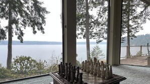 Ein Schachbrett auf einem Teppichboden, mit Blick auf einen See und Bäume durch große Fenster.