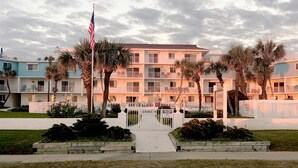 Ein mehrstöckiges Hotel mit Balkonen, Palmen und einer amerikanischen Flagge.