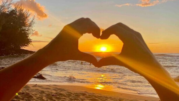 A sunset with hands forming a heart shape in the foreground. - Adventurers' Dream Launchpad: near Shops & Beaches: SUPs, Bikes, Snorkel & More! (Princeville)