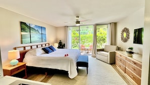 A bedroom with a bed, bedside table, lamp, and a view of the outdoors through a sliding door.