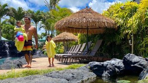 Un complexe hôtelier tropical doté d’une piscine, de chaises longues et d’un abri à toit de chaume.
