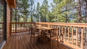 A wooden deck with a table and chairs, surrounded by a railing, overlooking a forest. - 1Bed/1Bath - Gorgeous Flagstaff Location with Pools, Golf, and More! (Flagstaff)