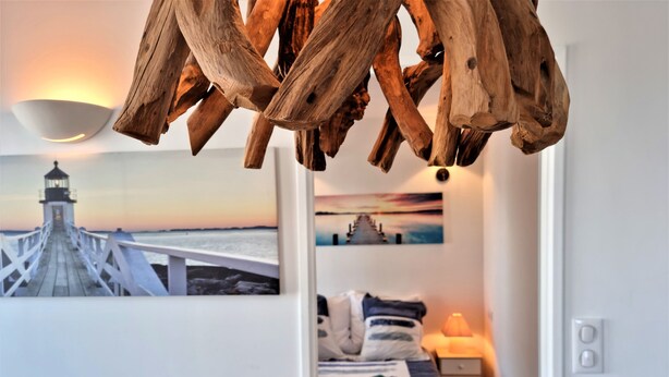 Une chambre à coucher avec un lit, une table de chevet, une lampe et une vue sur un phare, visible par la fenêtre.