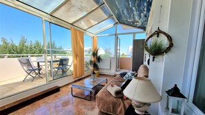 Une pièce baignée de lumière naturelle, avec un plafond en verre, un canapé, une table et une plante en pot.