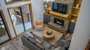Una sala de estar moderna con chimenea de piedra, televisor grande y una zona de estar acogedora.