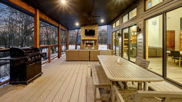 Una terraza exterior cubierta con una parrilla, zona de estar y una chimenea.