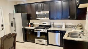 A modern kitchen with dark cabinetry, stainless steel appliances, and a granite countertop. - Private Two Bedroom, Two TVs, One Bathroom Casita! (Las Vegas)