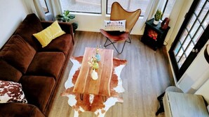 A cozy living room with a brown sofa, a wooden coffee table, and a cowhide rug.