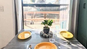 A dining table with two yellow plates, cutlery, and a potted plant.