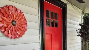Ein Haus mit roter Tür und einem dekorativen Blumenarrangement an der Wand.