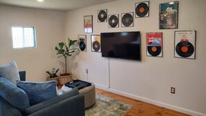 Ein Wohnzimmer mit Flachbildfernseher, einer Couch, einem Couchtisch und einer Pflanze.