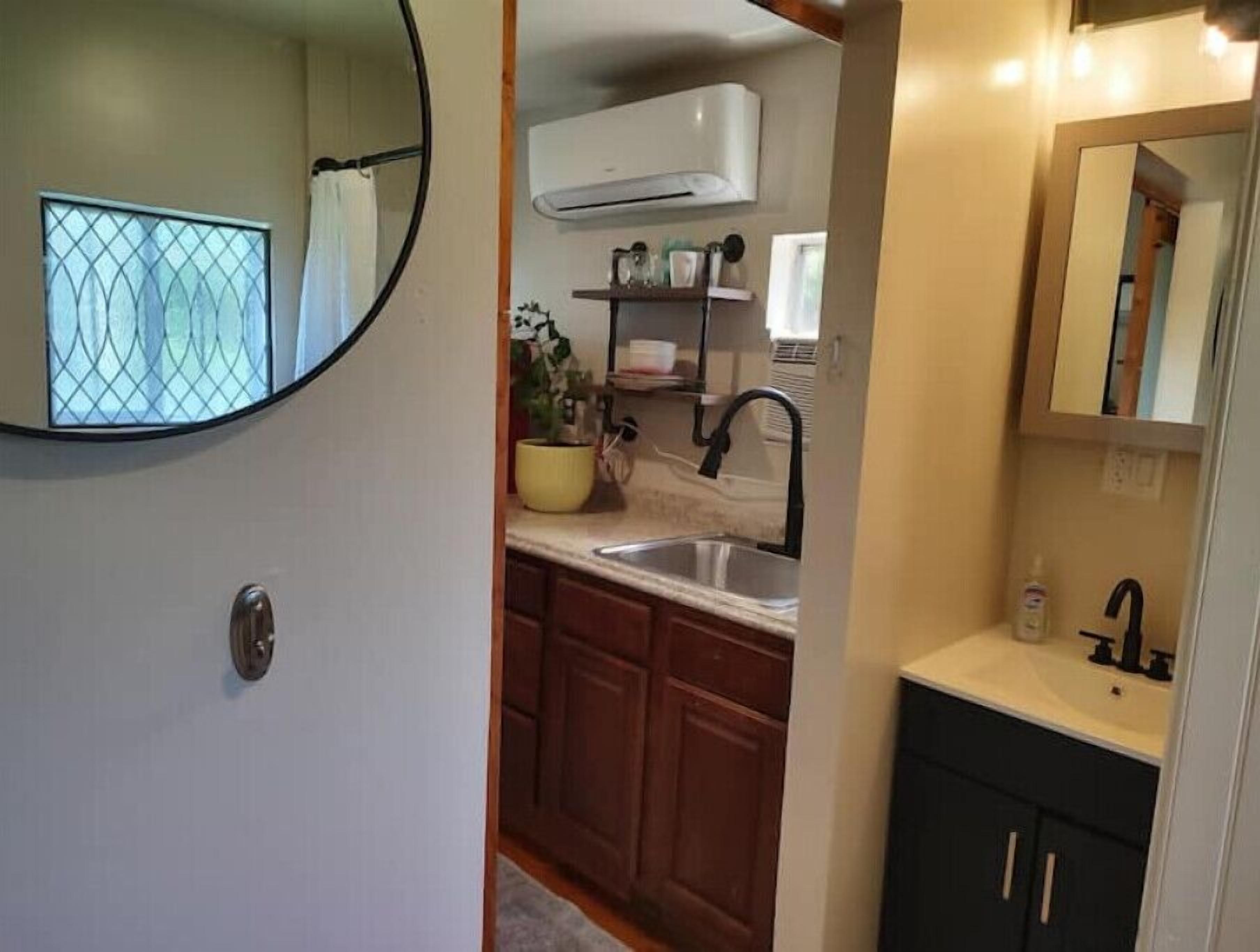 A compact kitchen with a sink, cabinets, and an air conditioning unit.