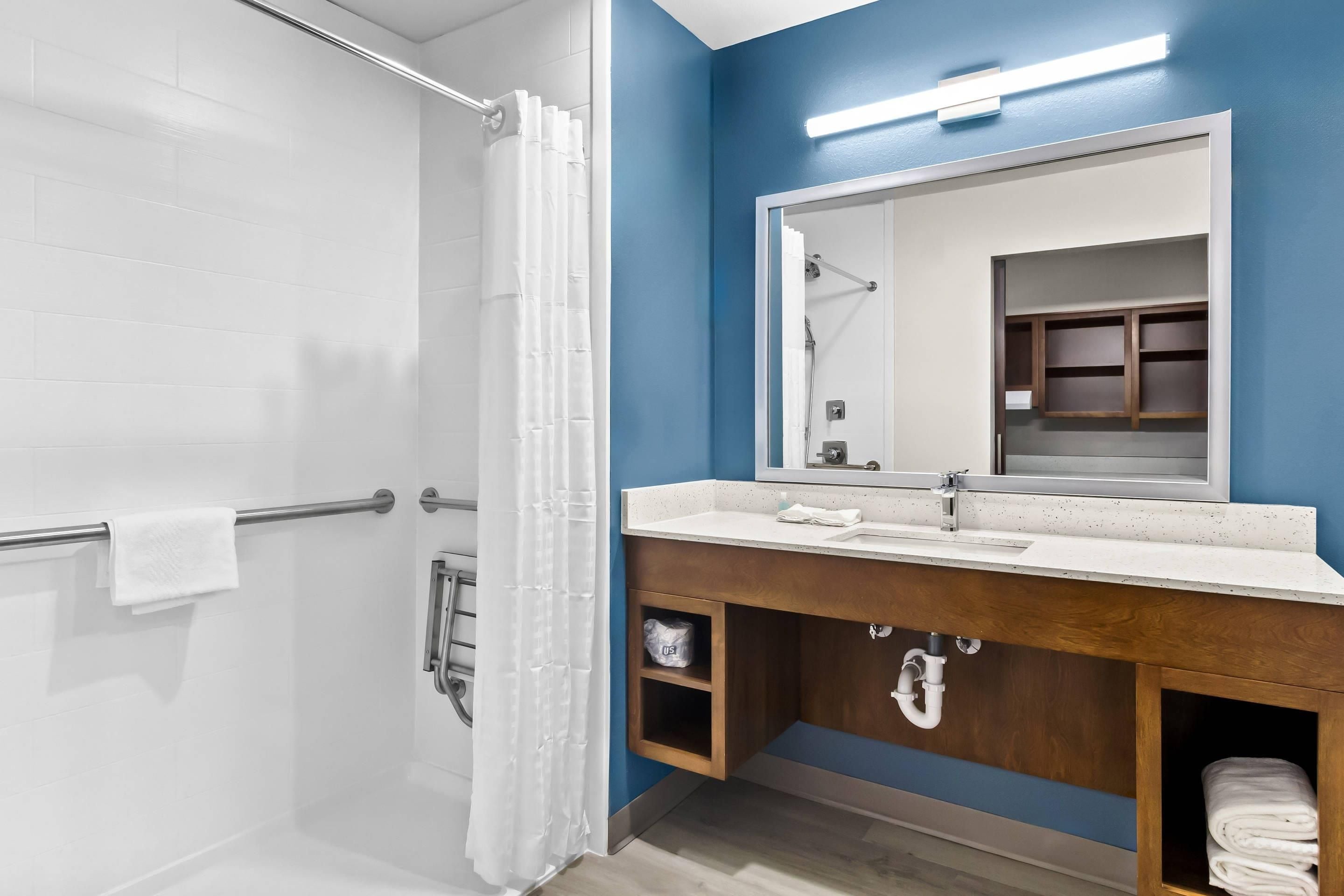 Une salle de bain avec une douche, un lavabo avec un miroir et un porte-serviettes.