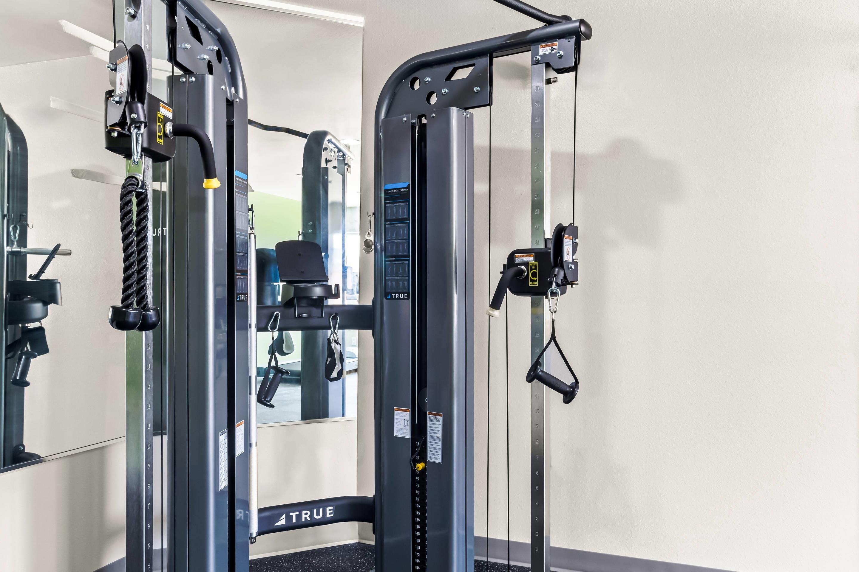 A gym with a weight machine labeled 'TRUE' and a mirror.