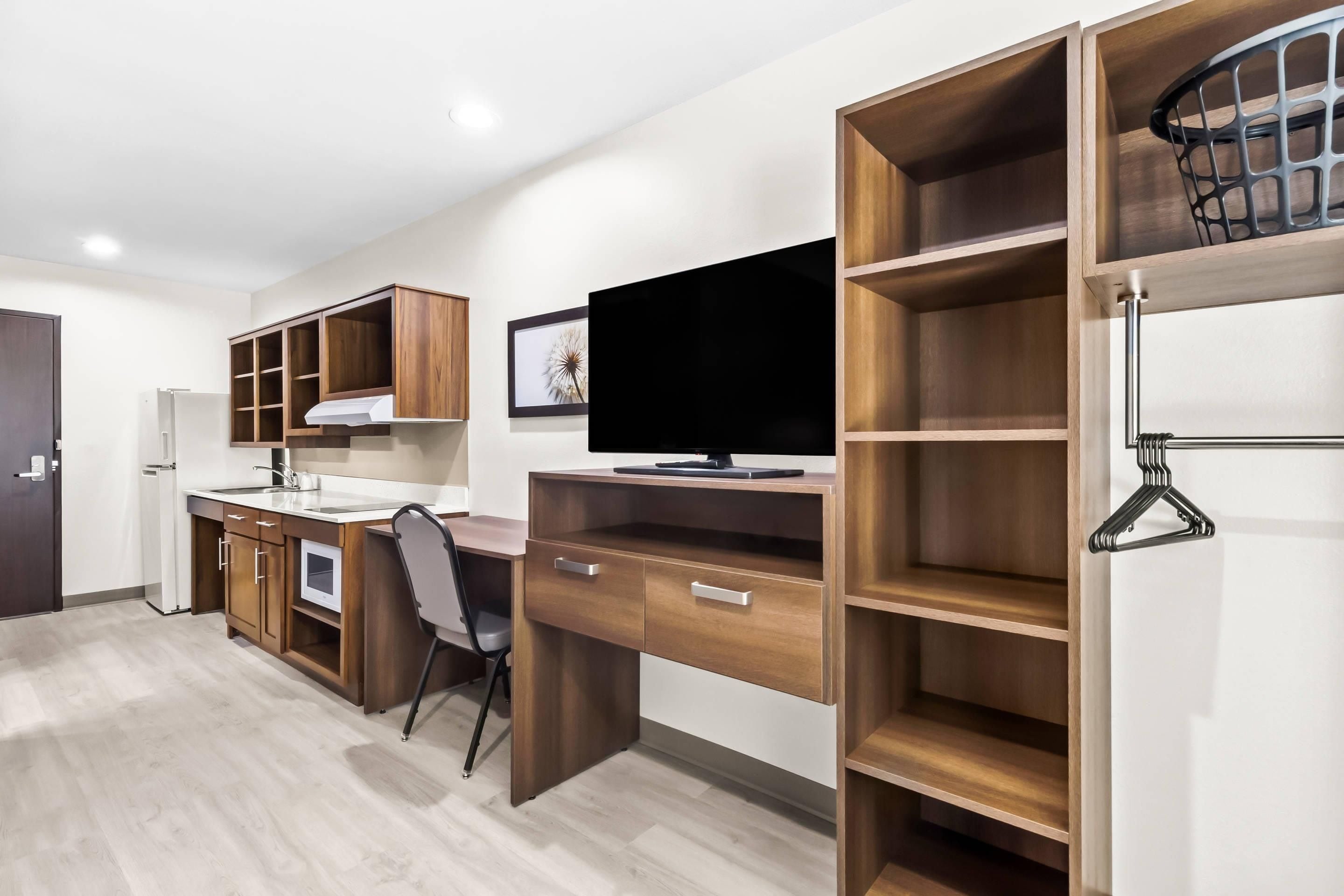 Una cocina moderna con armarios de madera, horno empotrado y un televisor de pantalla plana grande.