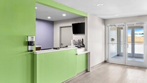 A modern bathroom with a green accent wall, a sink, a mirror, and a toilet. - Woodspring Suites South Houston Hobby (Houston)