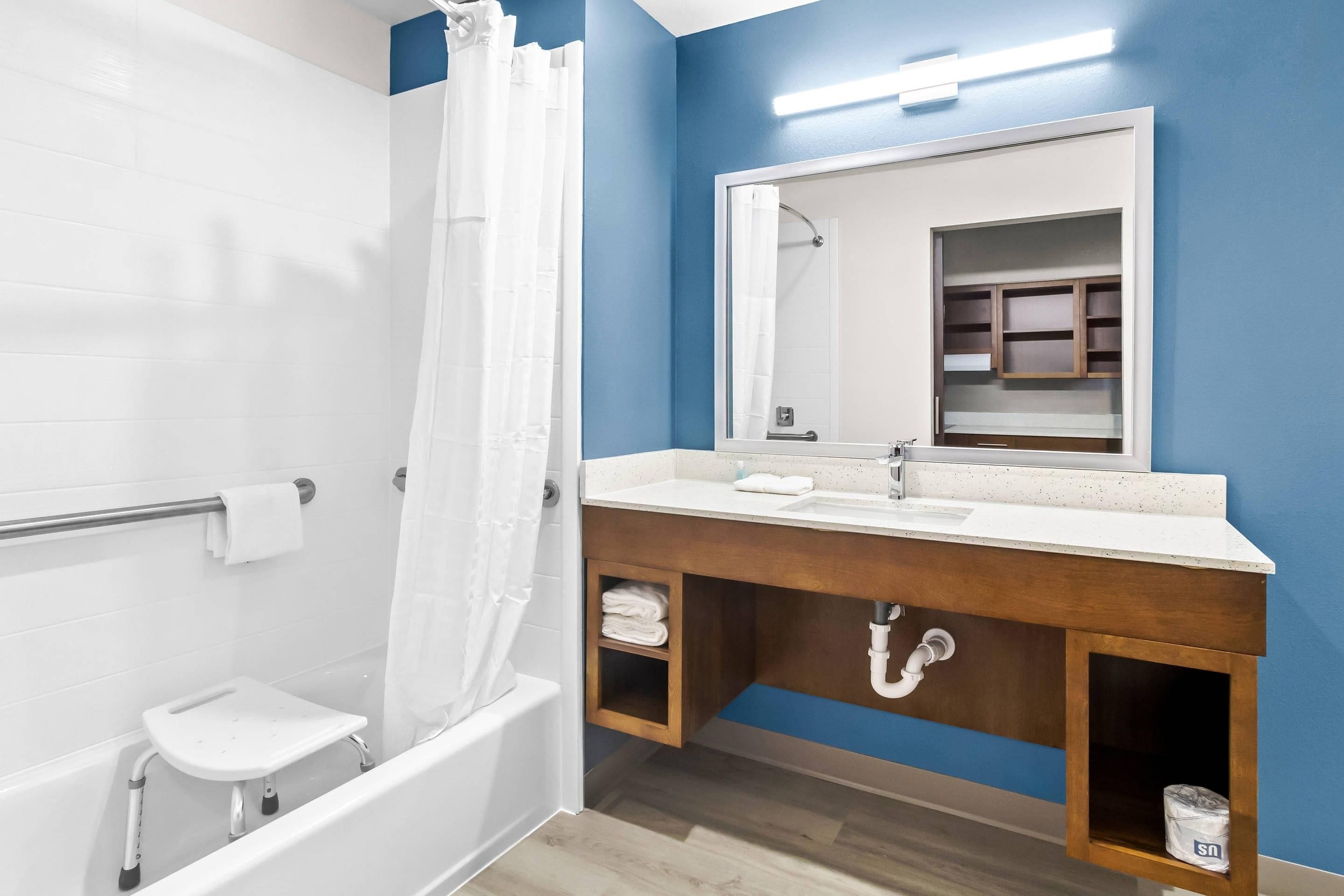 A modern bathroom with a bathtub, a shower, a sink with a mirror, and a towel rack.