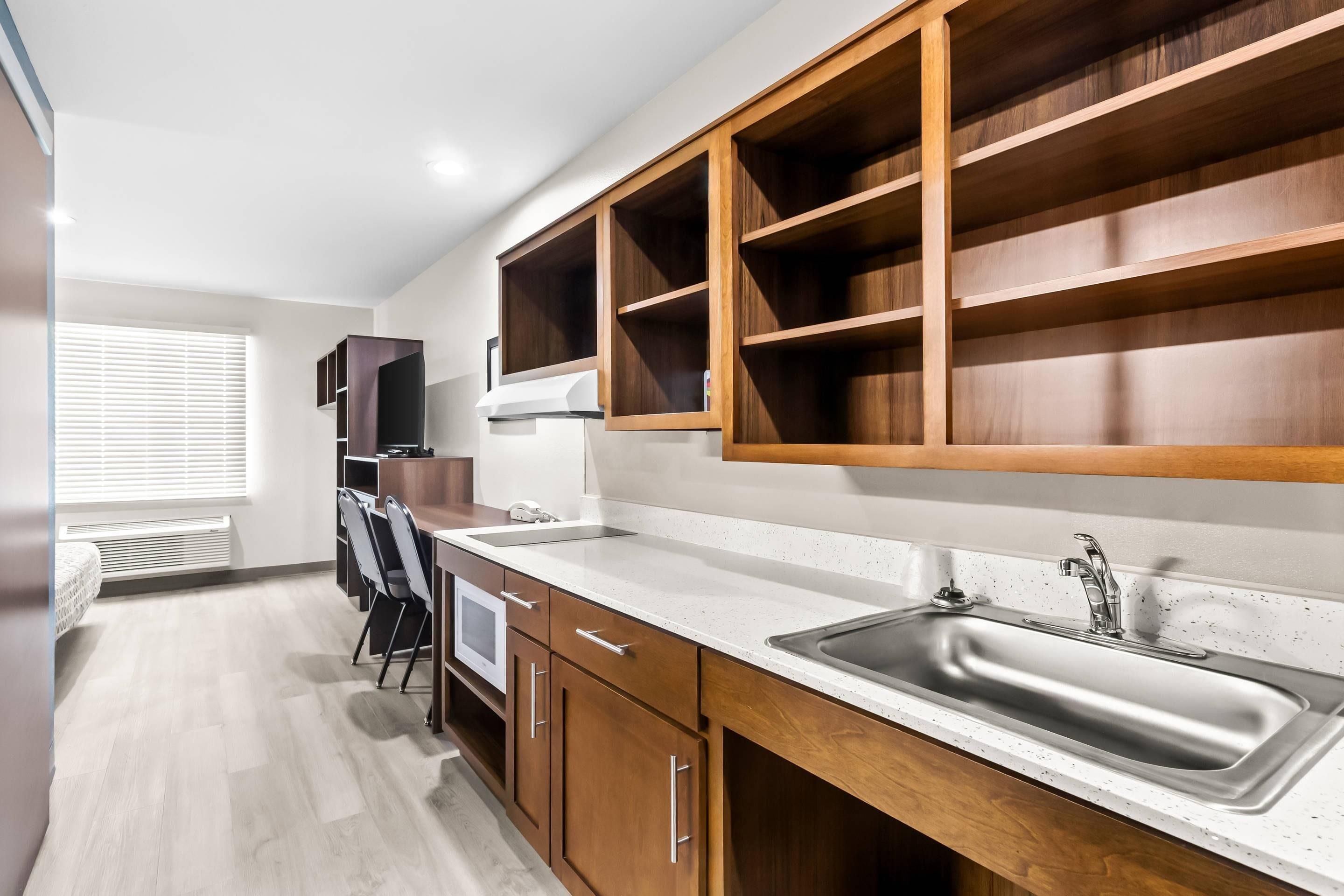A modern kitchen with wooden cabinets, a stainless steel sink, and a built-in oven.