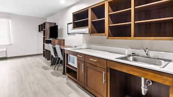 A modern kitchen with wooden cabinets, a stainless steel sink, and a microwave.