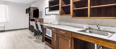 Een moderne keuken met houten kastjes, een RVS-spoelbak en een magnetron.